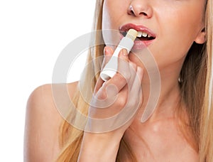 Closeup on happy teenage girl applying hygienic lipstick