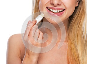 Closeup on happy teenage girl applying hygienic lipstick