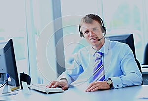 Happy young man working at callcenter, using headset.
