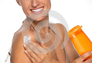 Closeup on happy woman applying sun screen bottle