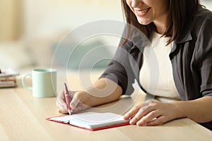 Closeup of happy woman writing on agenda at home