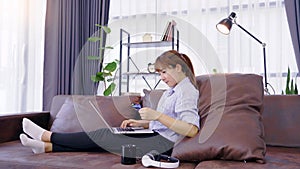 Closeup of happy young asian woman holding credit card inputting card information while and using laptop computer at home. Online