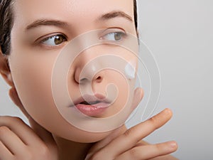 Closeup happy young woman applying cream to her face Skincare and cosmetics concept. Cosmetics. Woman face