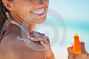 Closeup on happy young woman applying sun block creme