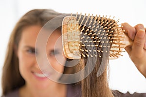 Closeup on happy young woman combing hair