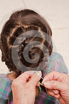 Closeup of head of asian kid. Grandmother is making of braids on little granddaughter`s