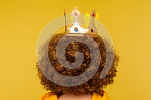Closeup of head with golden crown on curly afro hairdo, concept of superior privileged status, big ambitions photo