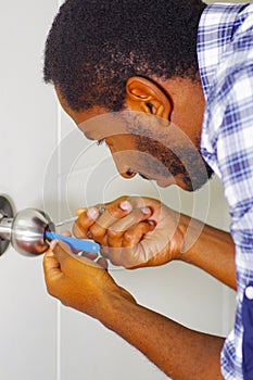 Closeup head and hands of locksmith using pick tools to open locked door