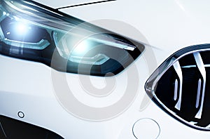 Closeup headlamp light of a white luxury car. Automotive industry concept. Electric car or hybrid vehicle concept. Automobile