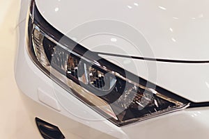 Closeup headlights of car white body close-up.