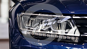 Closeup headlights of a modern blue color car. Detail on the front light of a car. Modern and expensive car concept.