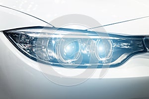 Closeup headlights of modern car during turn on light in night.