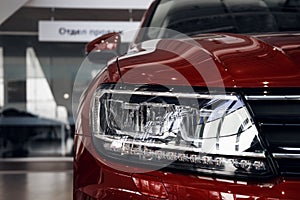 Closeup headlights of a modern red color car. Detail on the front light of a car. Modern and expensive car concept