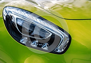 Closeup headlights of modern sport green car. Car exterior deta