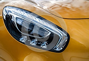 Closeup headlights of modern sport yellow car. Car exterior deta