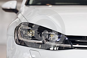 Closeup headlights of a modern white color car. Detail on the front light of a car. Modern and expensive car concept