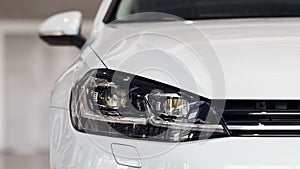 Closeup headlights of a modern white color car. Detail on the front light of a car. Modern and expensive car concept