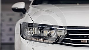 Closeup headlights of a modern white color car. Detail on the front light of a car. Modern and expensive car concept