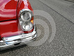Closeup of the headlights of a vintage red car parked outdoors