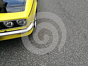 Closeup of the headlights of a vintage yellow car parked outdoors