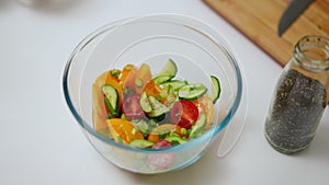 Closeup healthful organic salad in bowl and pepper spice in glass bottle on table. Close-up delicious fresh lunch in