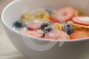 Closeup of healthy breakfast with corn flakes and berries in white bowl