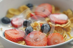 Closeup of healthy breakfast with corn flakes and berries in white bowl