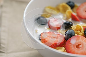 Closeup of healthy breakfast with corn flakes and berries in white bowl