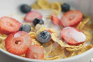 Closeup of healthy breakfast with corn flakes and berries in white bowl