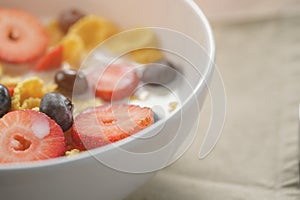 Closeup of healthy breakfast with corn flakes and berries in white bowl