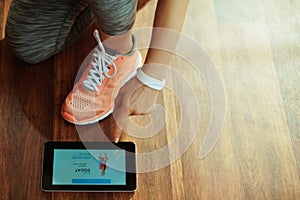 Closeup on woman using online coaching fitness app in tablet PC