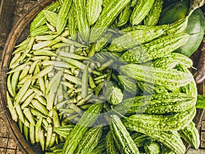 Closeup heap of momordica and okra in braided basket. Harvested young fresh organic bio antiparasitic, anthelmintic raw photo