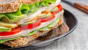 Closeup hearty sandwich with sliced turkey, lettuce, tomatoes. home made food. Tasty healthy meal