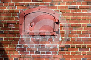 Closeup of heavy red iron door in weathered brick wall, as an industrial background