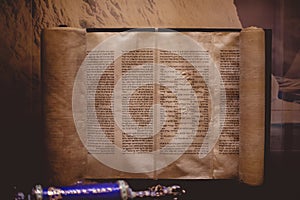 Closeup of a Hebrew Bible written on a parchment roll on the table under the lights