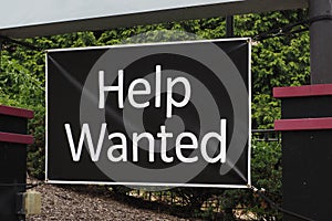 Closeup of a "Help Wanted" sign on a railing outdoors
