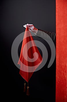 Closeup hiding magician hand behind red drapery holding magic handkerchief