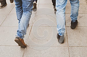 Closeup high angle shot of two males legs walking on a sidewalk