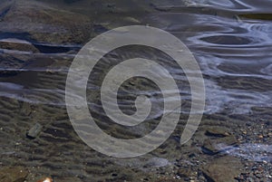 Closeup high angle shot of wavy water with the sand and rocks underneath