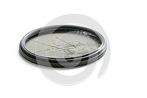 Closeup high angle studio shot of black circular polarizer filter with cracked glass, isolated on white background