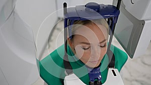 Closeup high-angle view of young female patient standing in dental x-ray machine for dental radiography. Concept of