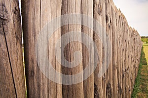 Closeup high old wooden fence of logs in form of palisade