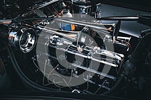 Closeup of a high-shine chrome car engine in a dark, industrial setting.
