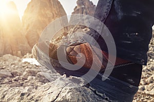 Closeup of a hiking shoe, the sun shines through the mountains