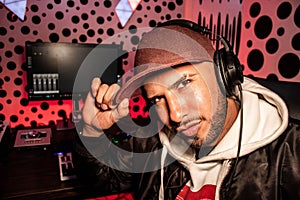 Closeup of a Hispanic DJ holding his hat with musical instruments in the background