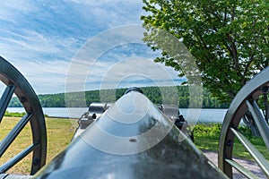 Closeup of a historic black powder cannon standing guard over a shoreline