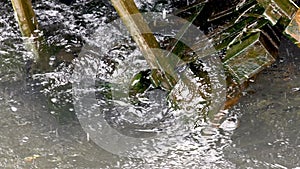 Closeup of historic wooden wheel spinning into flowing water in canal