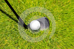 Closeup of hitting golf ball with golf iron club golf course wih motion blur effect