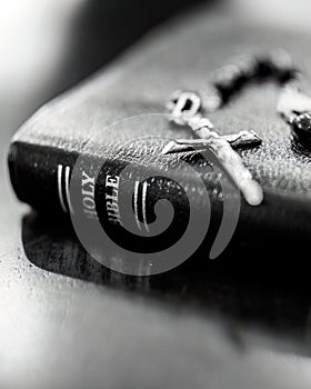 Closeup of the Holy Bible with catholic crucifix and prayer beads laying on top
