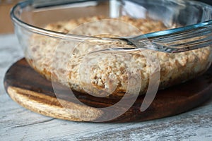 Closeup of homemade apple crisp crumble cake in glass form on a wooden surface, selective focus